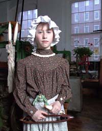 Young girl in 1850's dress - standing in weave room