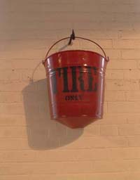 Red fire water bucket- hanging on a hook on the wall.