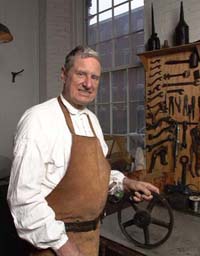 man wearing apron standing by  set of hand tools.